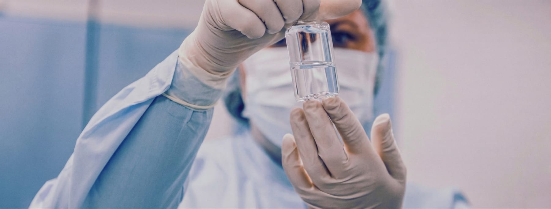 Técnico de laboratorio examinando un vial en un entorno estéril